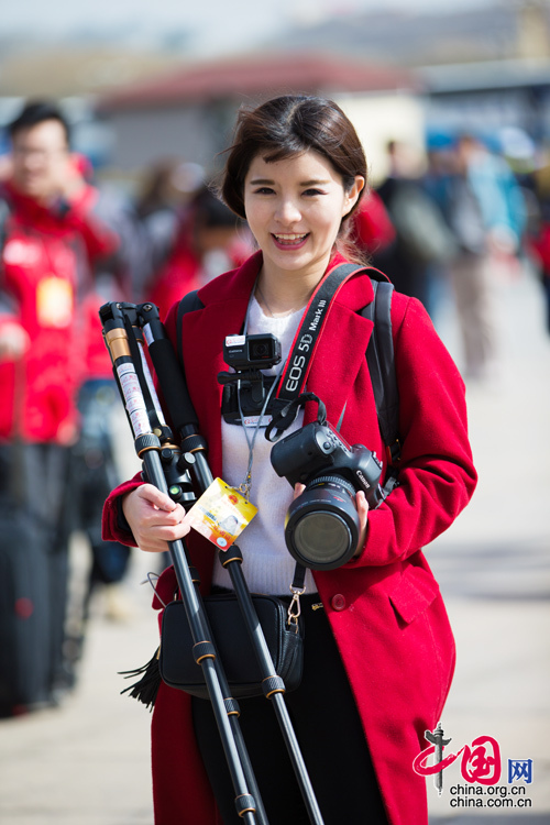 2016年兩會(huì)，人民大會(huì)大堂前，一位笑容燦爛的紅衣女記者正步入大會(huì)堂。中國(guó)網(wǎng) 鄭亮 攝